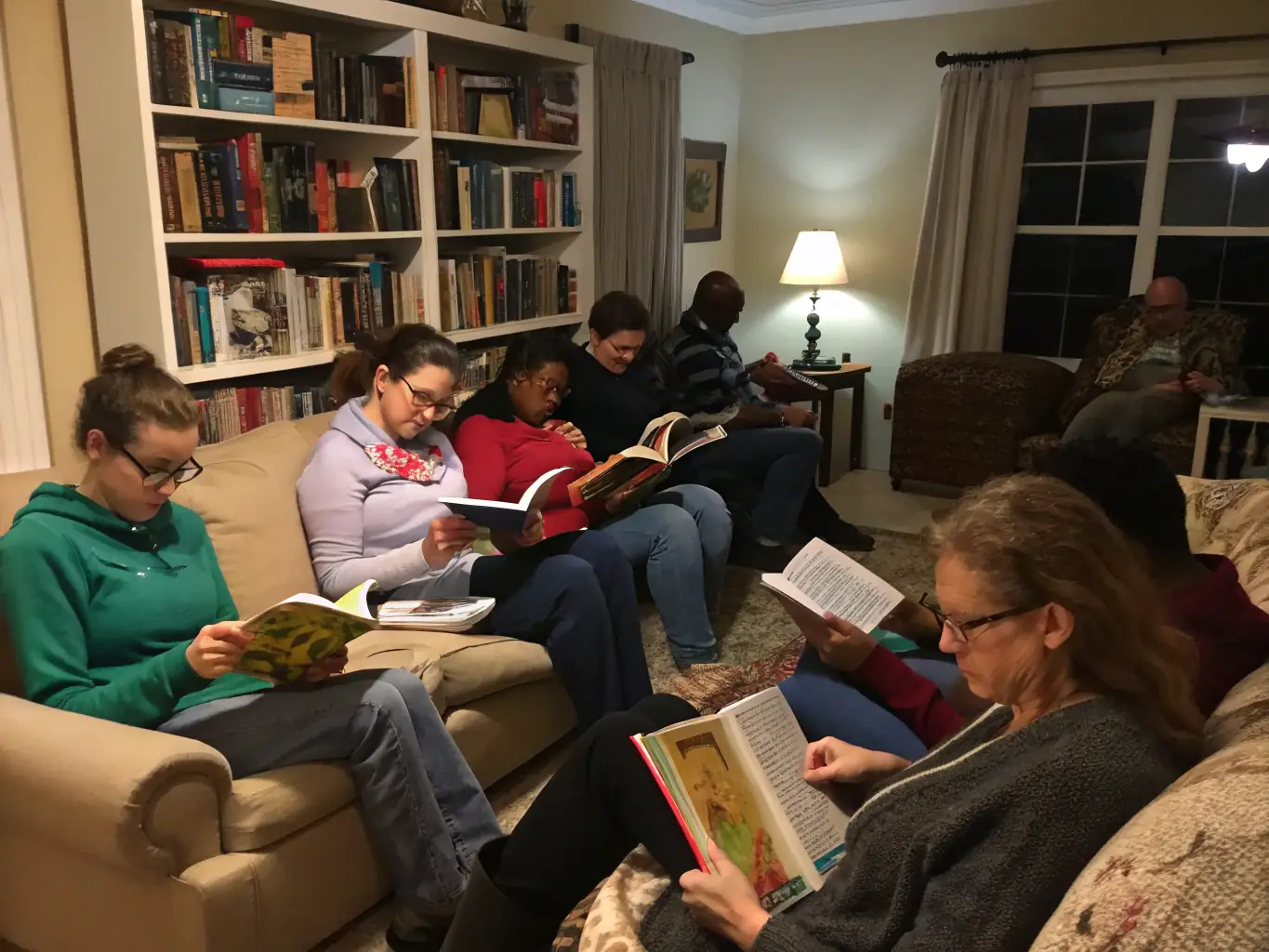 A diverse group of people of different ages reading books together in a cozy library setting, symbolizing community and shared learning.